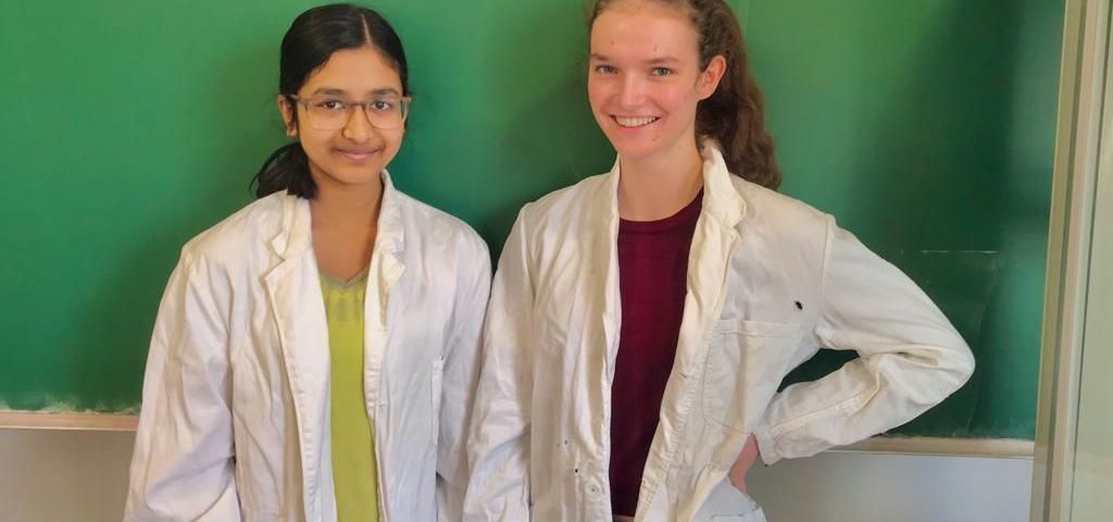 Zwei Schülerrinnen stehen vor einer Tafel