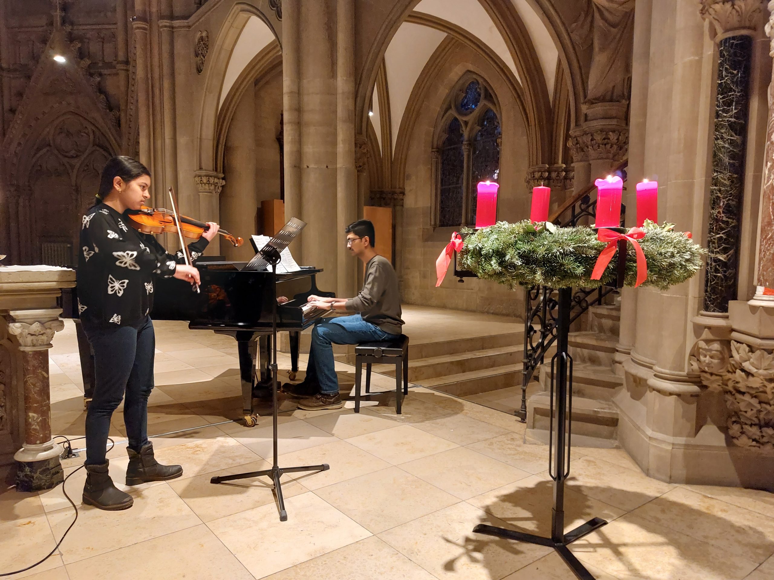 Zwei Personen spielen ein Klavier und eine Geige in einer Kirche.