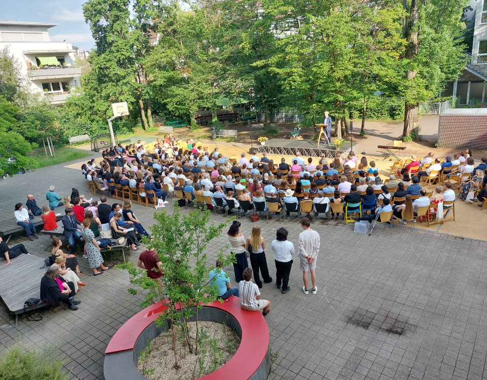 Blick von oben auf Schulhof auf welchem Abi ausgabe stadfindet, Herr Wolnitz spricht auf Schulhof