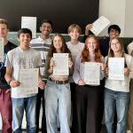 Mehrere Personen bei einem Gruppenfoto zeigen stolz ihre Cambridge Zertifikate