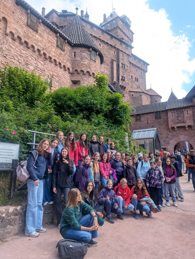 Mehrere Personen posieren für ein Gruppenbild vor einer Burg