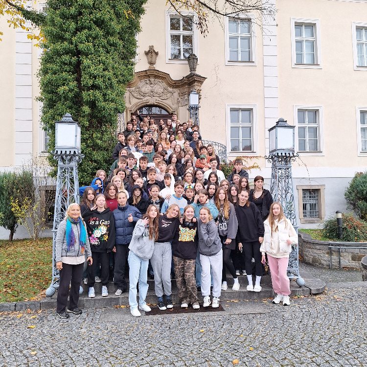 Viele Personen auf einem Gruppenbild vor einem Schloss